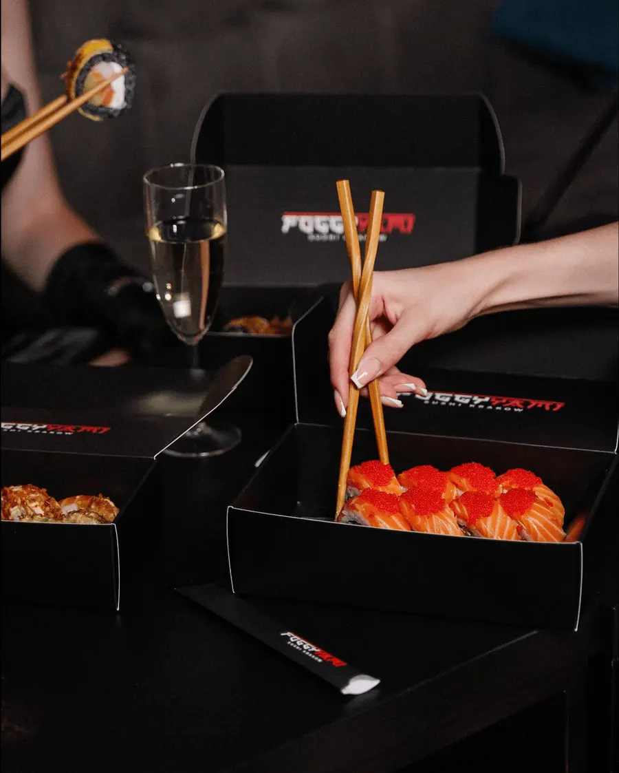 Salmon sushi rolls topped with red caviar served in a Foggy Krakow box with a glass of sparkling wine
