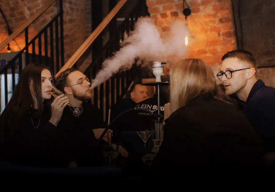 Guests enjoying cocktails at a candlelit table beside an exposed brick wall
